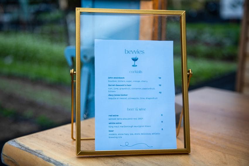 A printed drinks menu in a brass frame