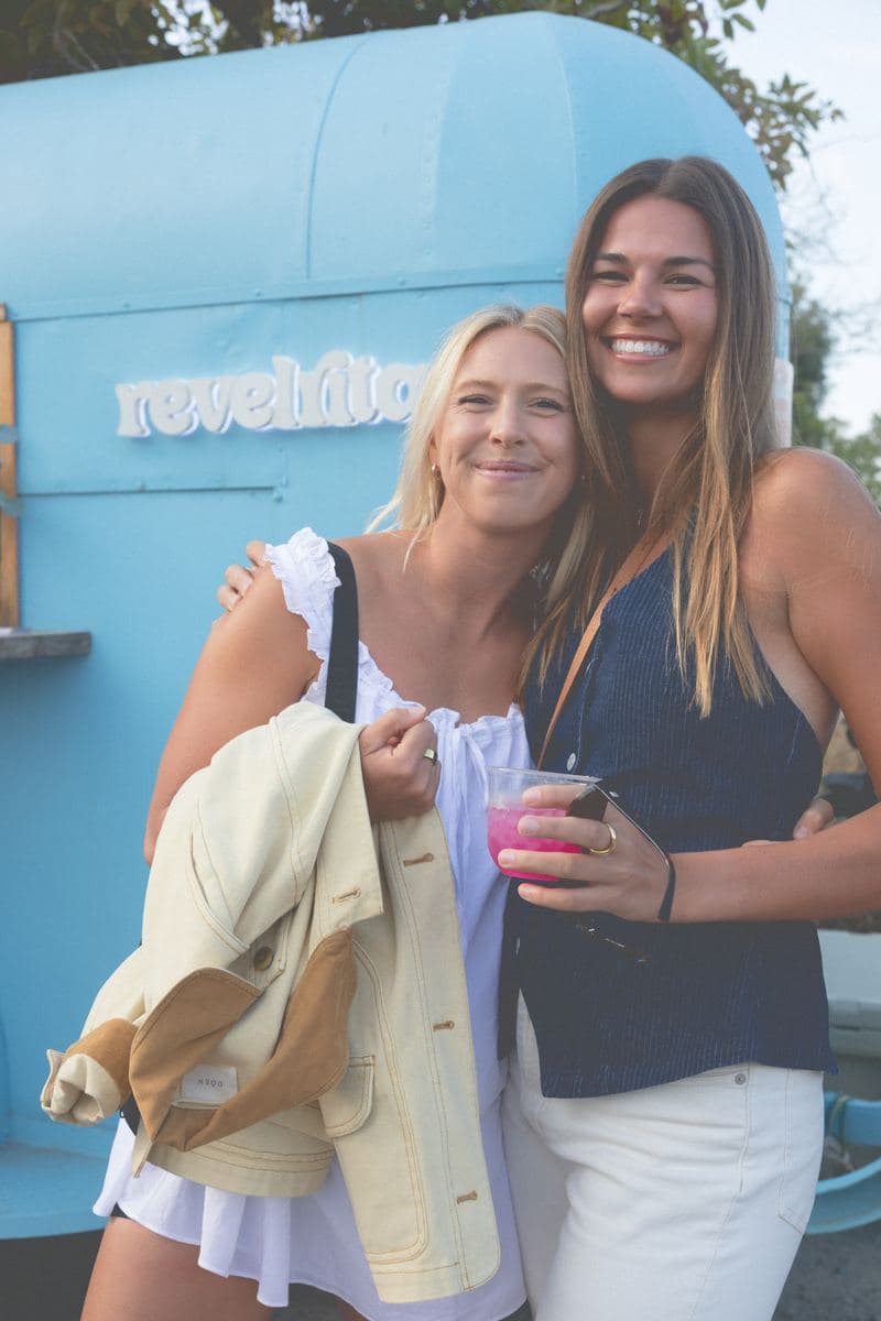 Two friends hugging in front of the revelrita sign