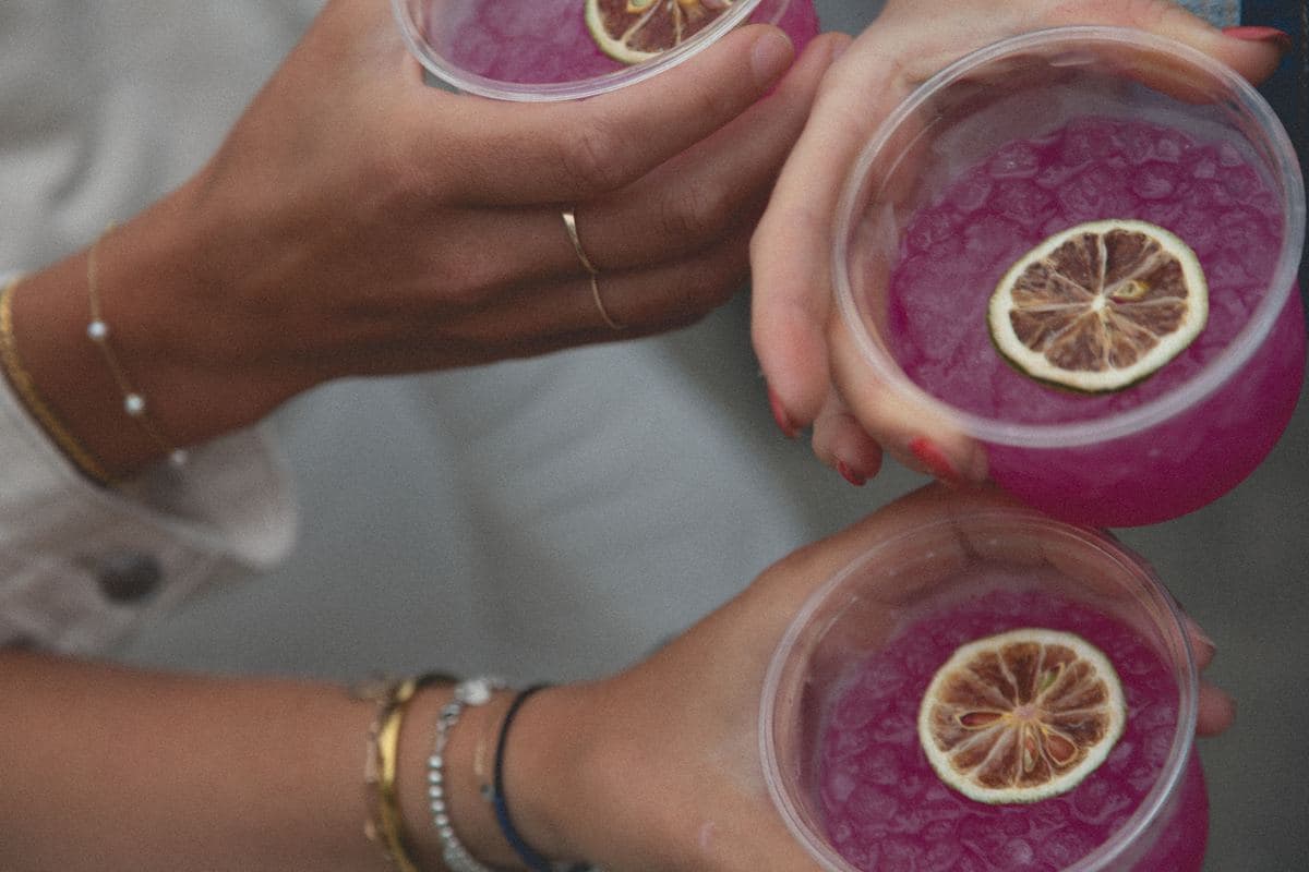 Hands holding pink margaritas from above