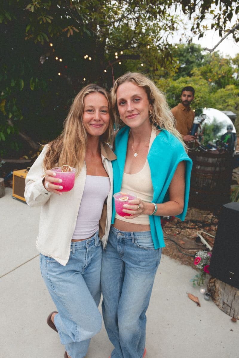 Two friends with drinks under the string lights