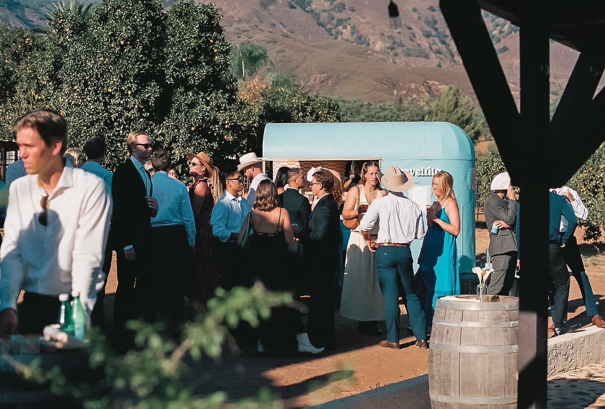 Wedding guests gathered around the cart in an orange grove